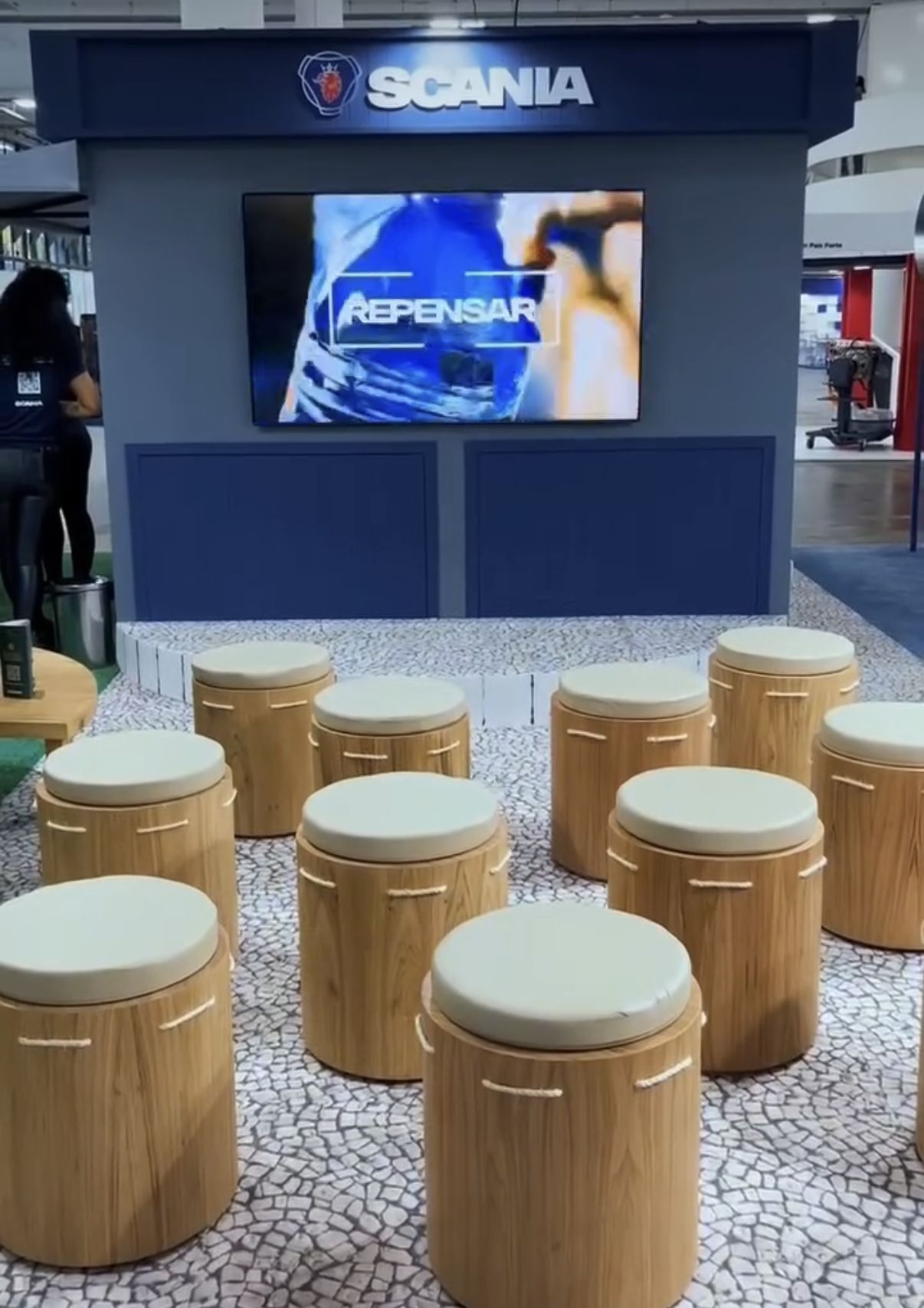 Lounge com pufes de madeira e painel de vídeo