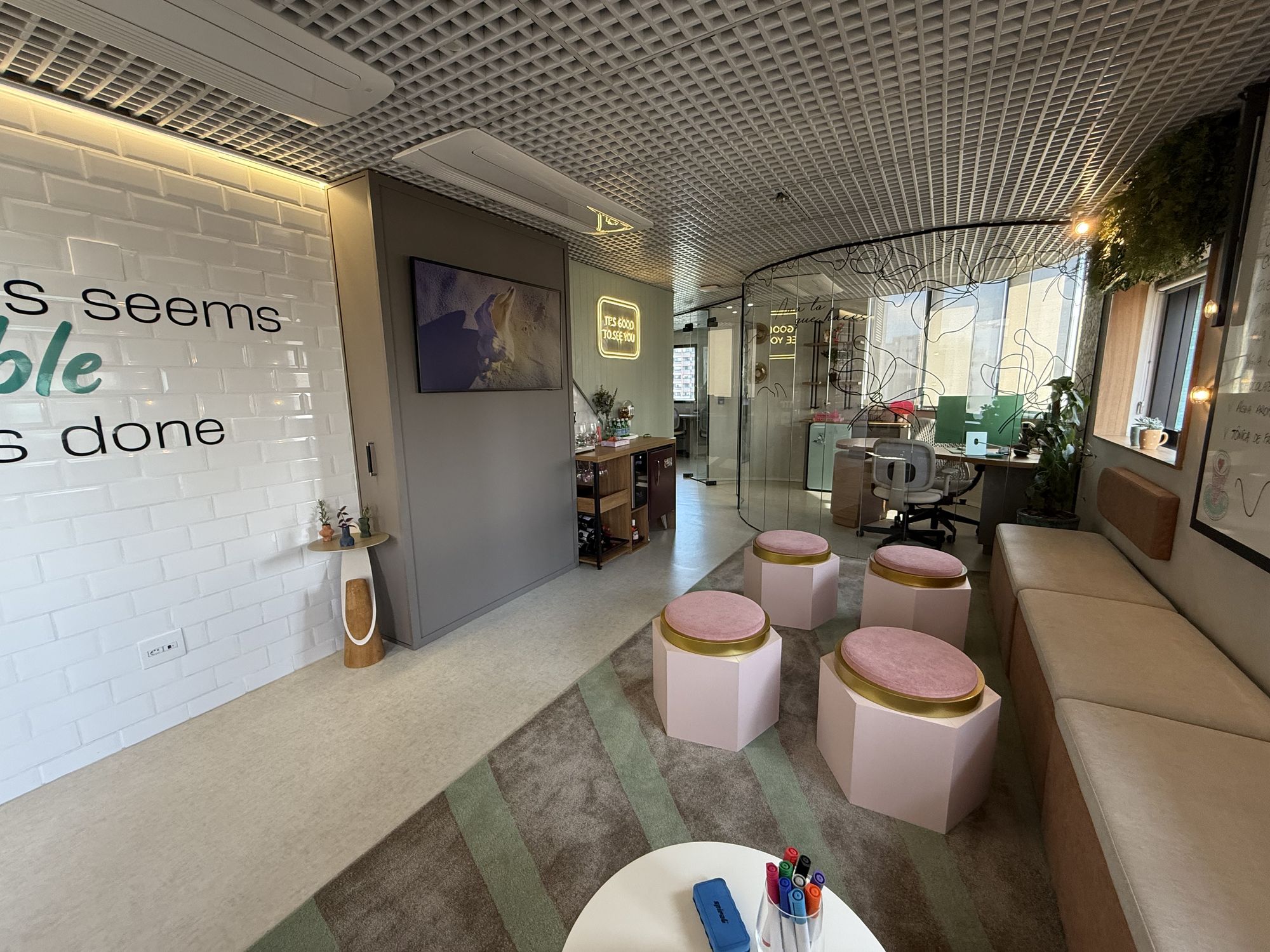 Lounge com pufes, banco contínuo e parede de azulejos