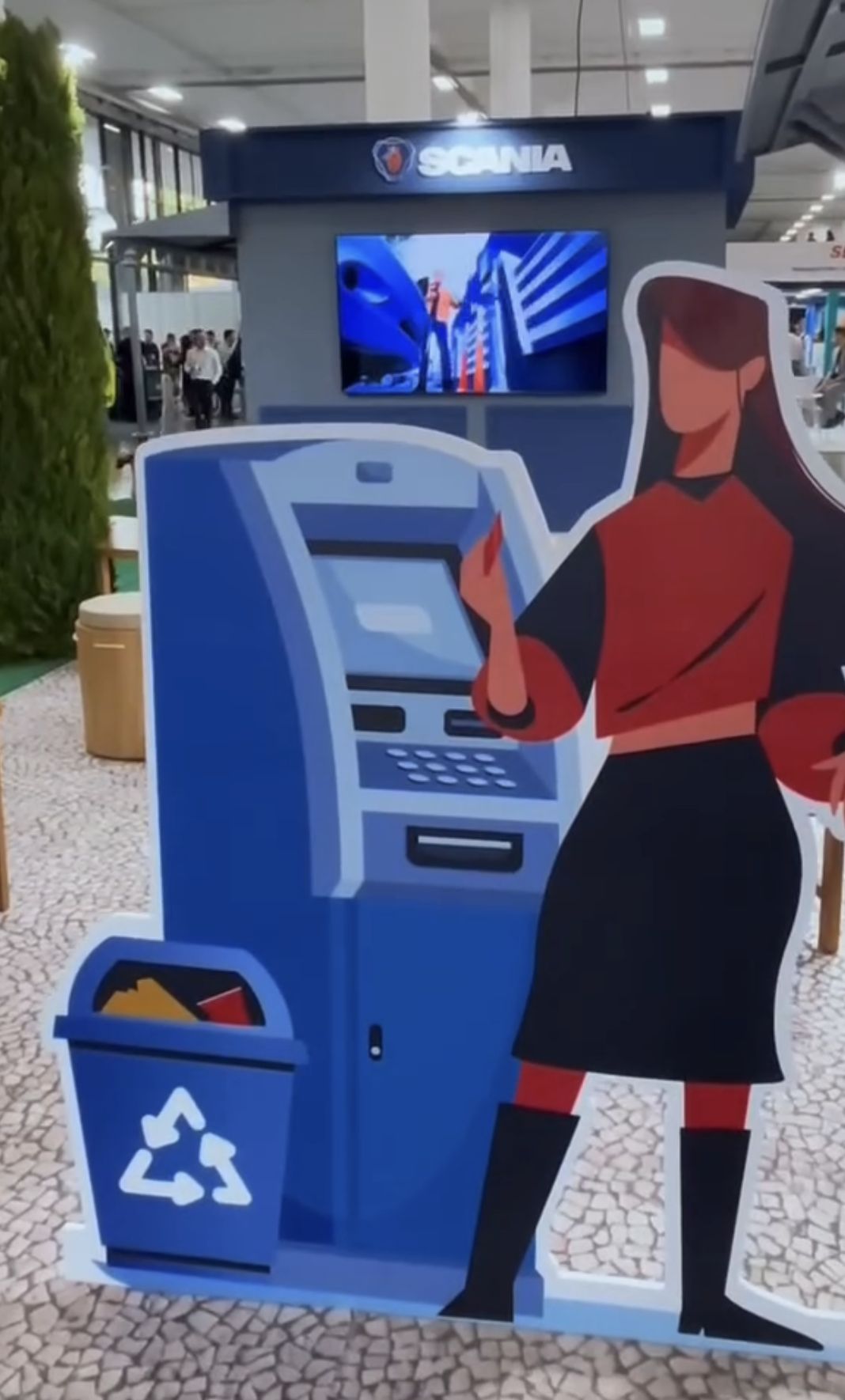 Totem ilustrado ao lado de painel de vídeo