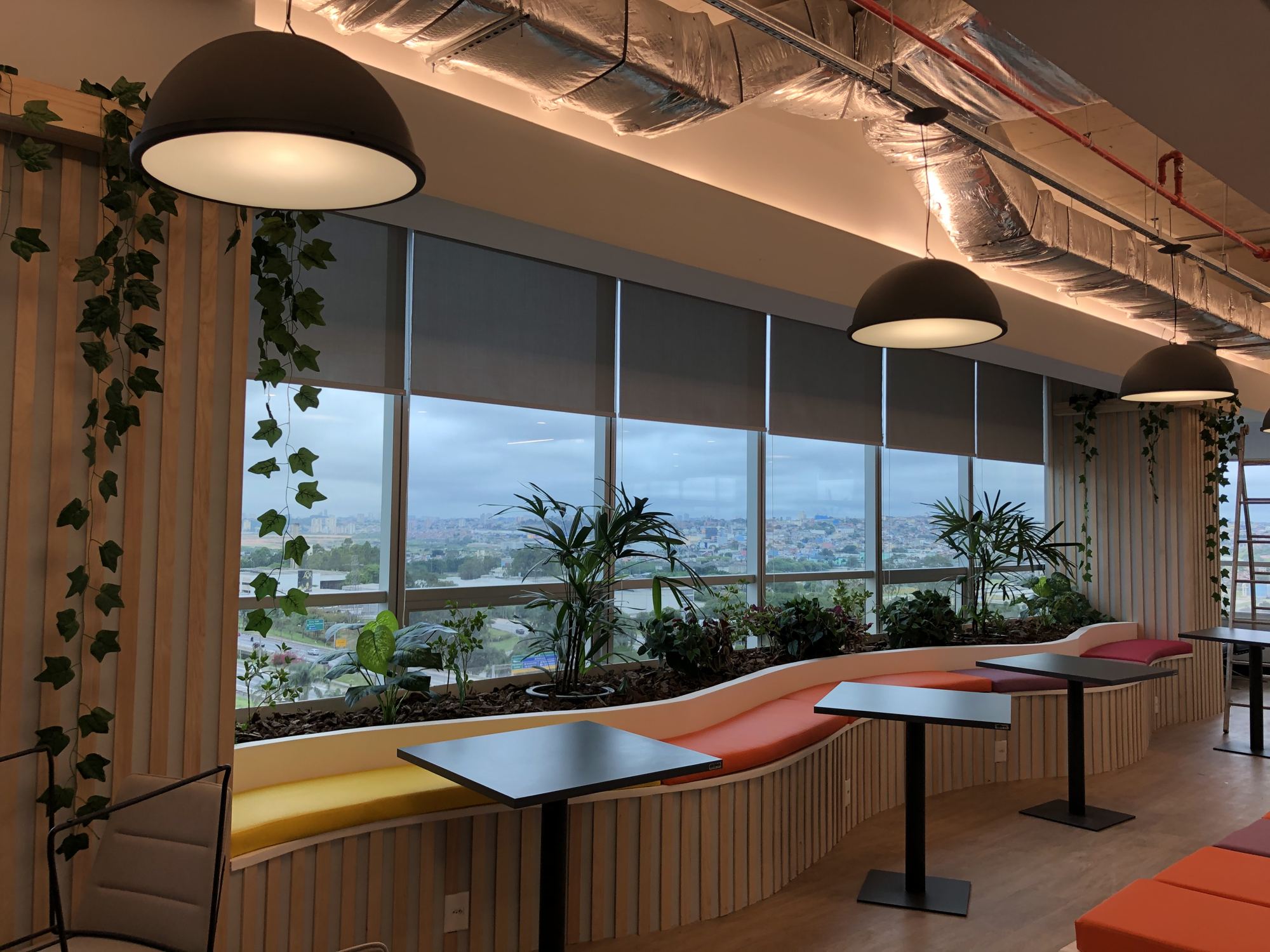 Escritório com banco curvo, plantas e vista da cidade